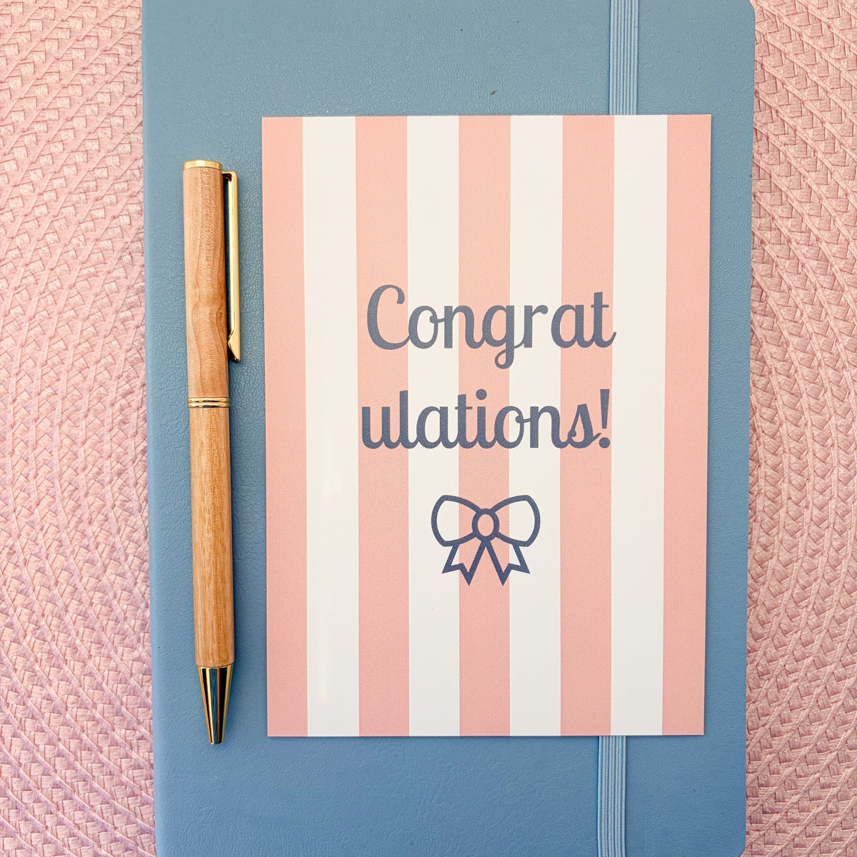 Congratulations postcard with pink and white stripes and a blue bow design