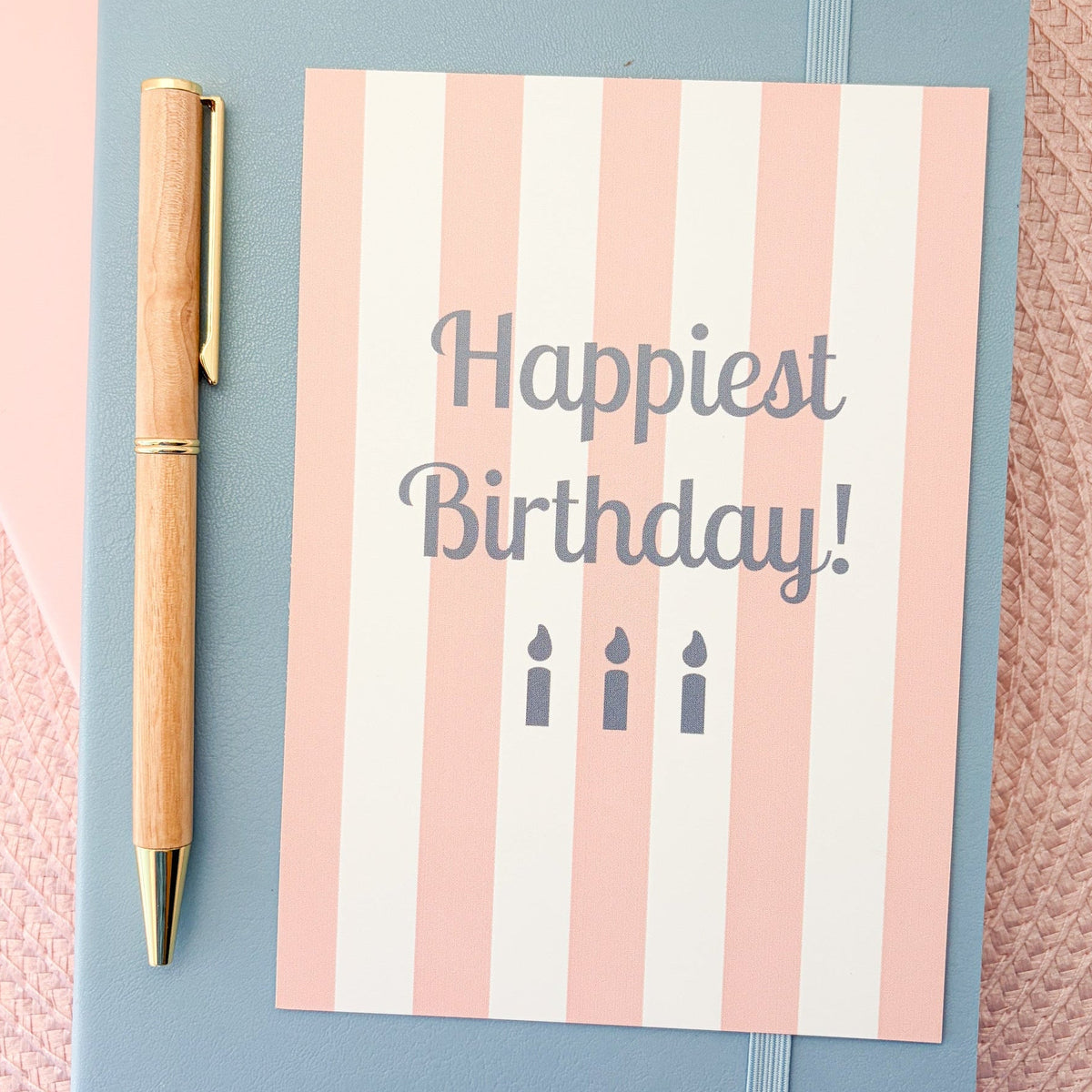Happiest Birthday postcard with a pink and white striped design and blue candles