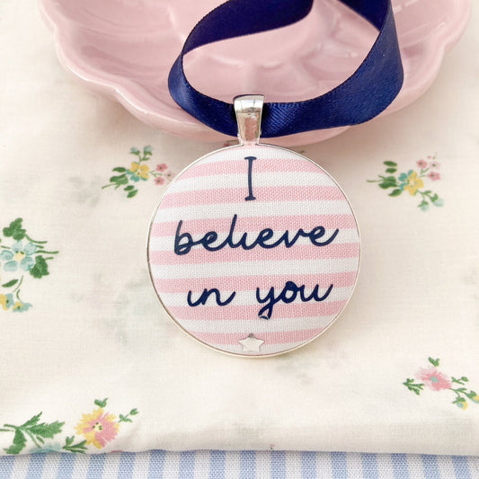 Keepsake with I believe in you printed in navy on a pink and white striped fabric, with a navy blue ribbon