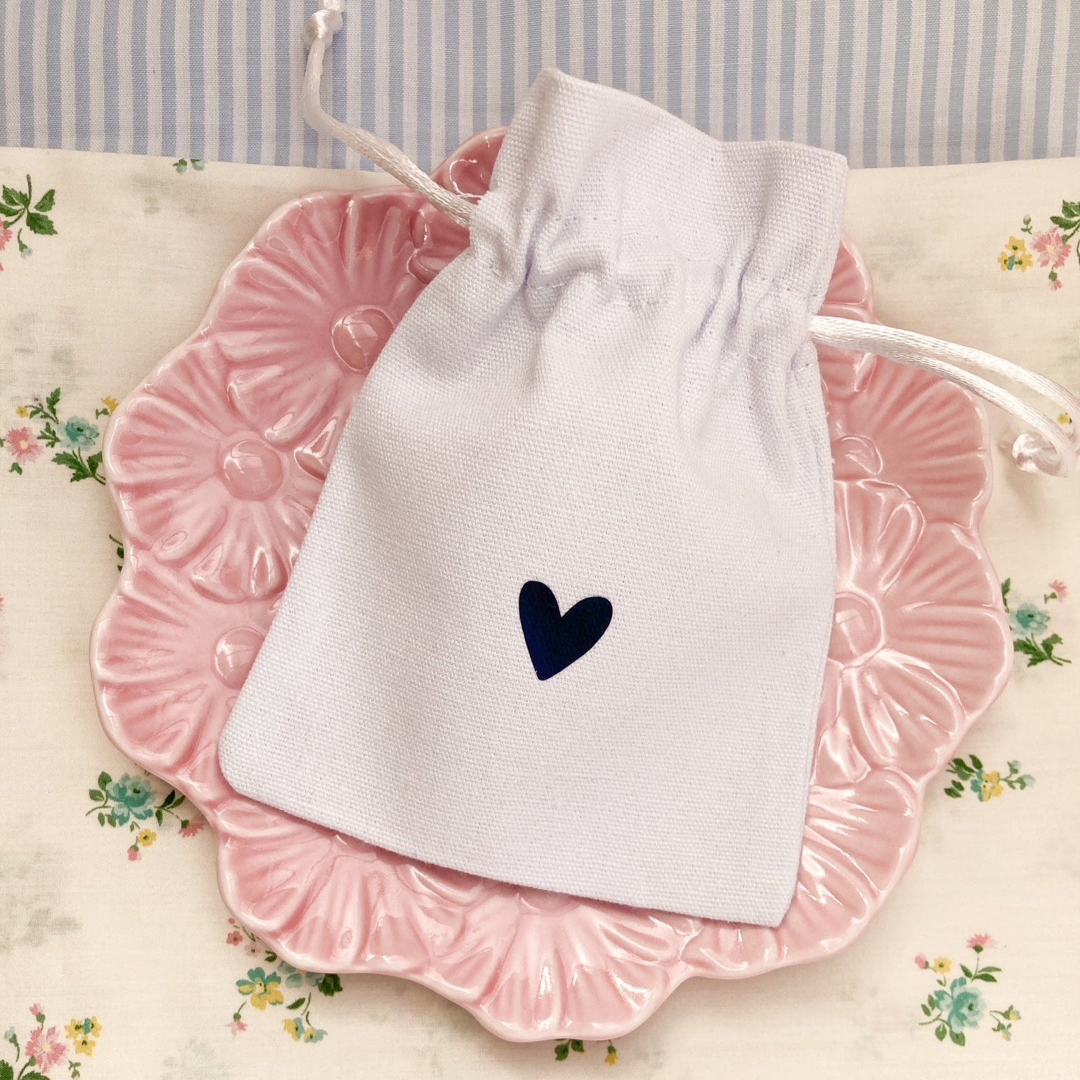 White keepsake gift pouch with a printed small navy blue heart