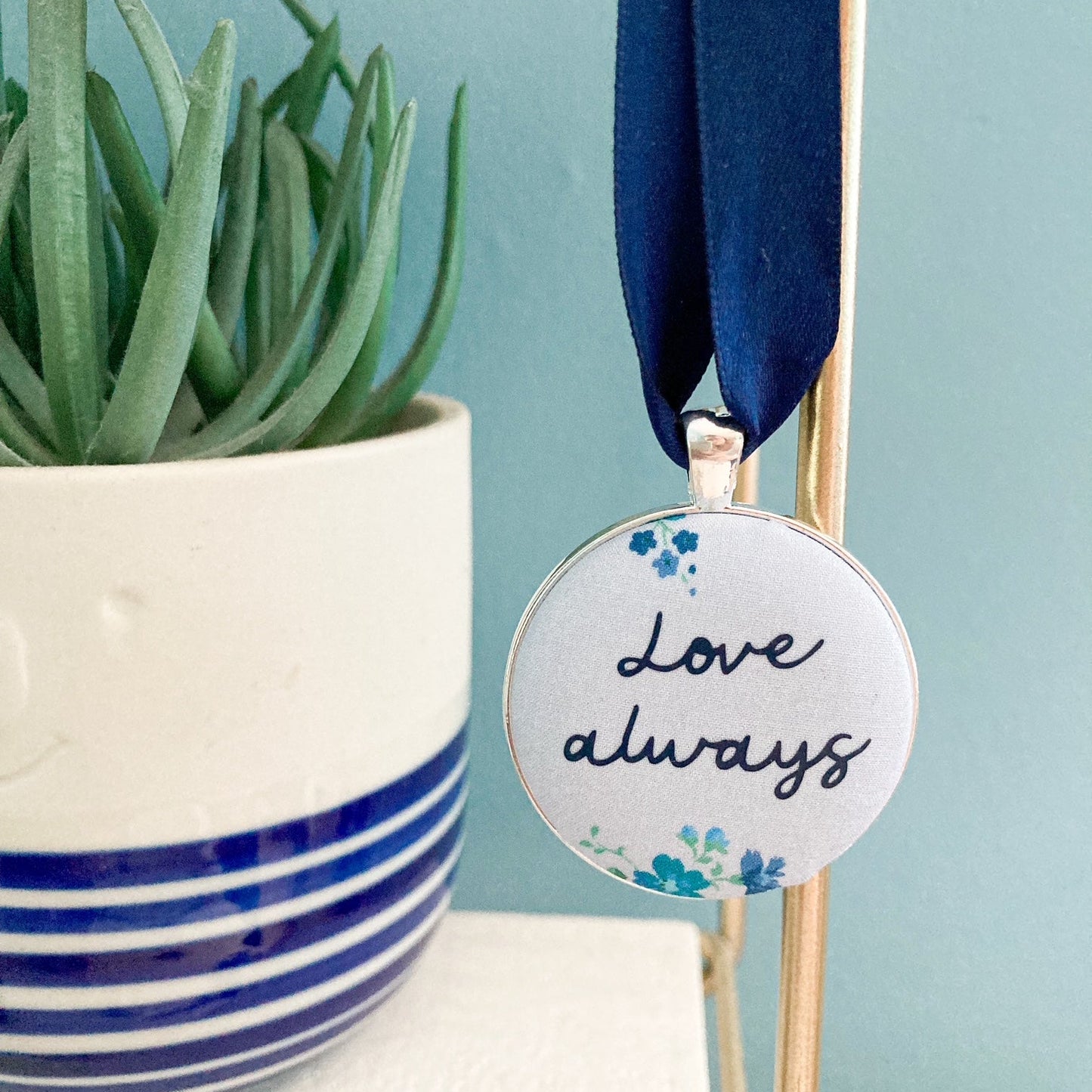 Keepsake with Love Always printed on a blue floral fabric with a navy blue ribbon