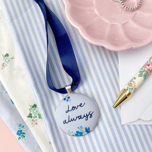 Keepsake with Love Always printed on a blue floral fabric with a navy blue ribbon