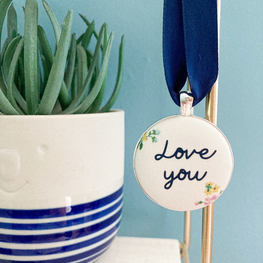 A Love You keepsake printed onto cream & floral fabric with a navy blue ribbon