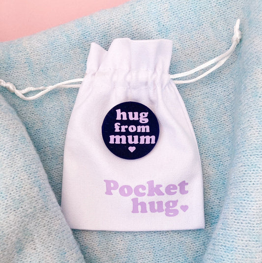 Hug From Mum badge in navy and lilac with a white drawstring gift pouch printed with "Pocket Hug" in lilac