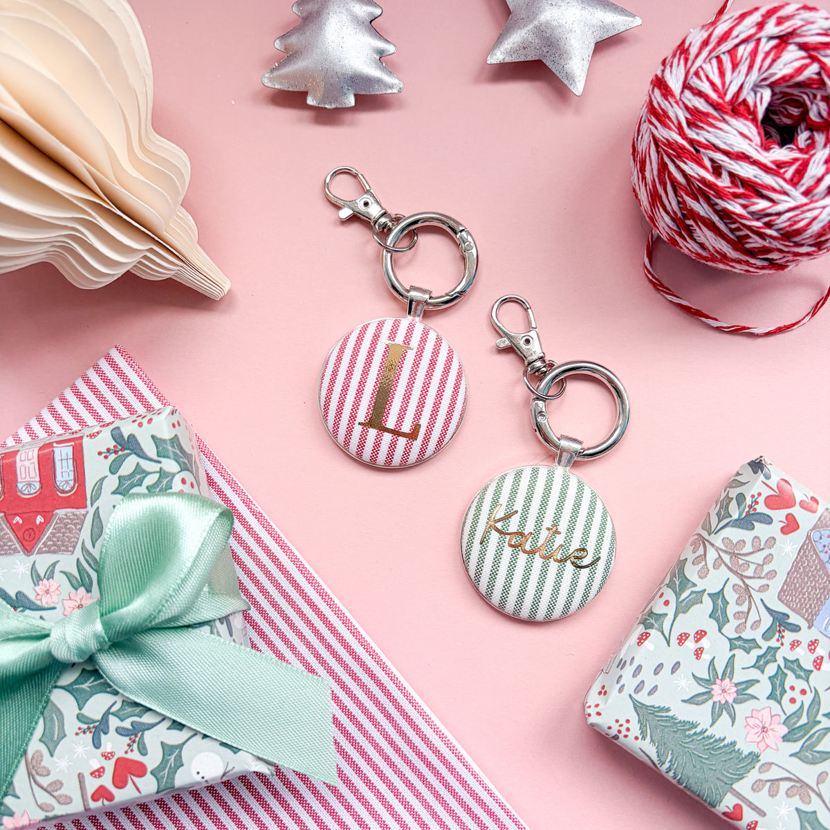 Personalised Christmas Gift Tag and Keyring, made with festive green striped fabric, printed with Katie in gold foil, set in a keyring on a Christmas flatlay