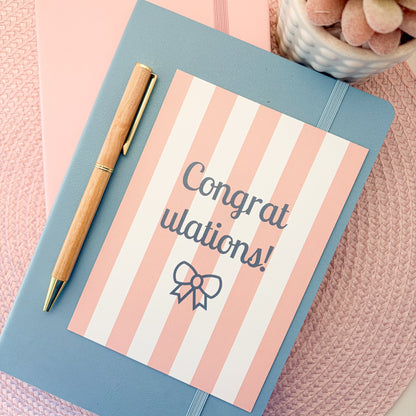 Congratulations postcard with pink and white stripes and a blue bow design