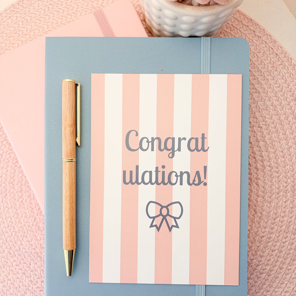 Congratulations postcard with pink and white stripes and a blue bow design