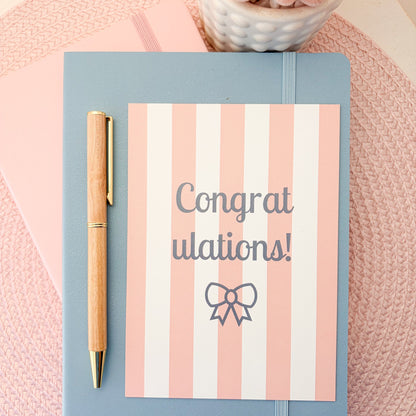 Congratulations postcard with pink and white stripes and a blue bow design