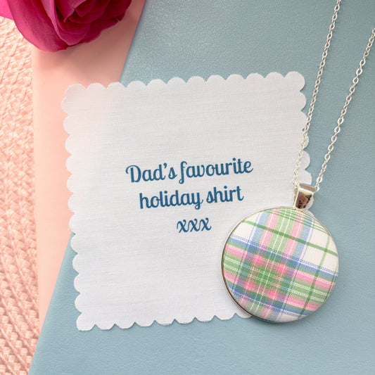 Checked necklace on a 'Dad's favourite holiday shirt' fabric message, placed on a blue notebook