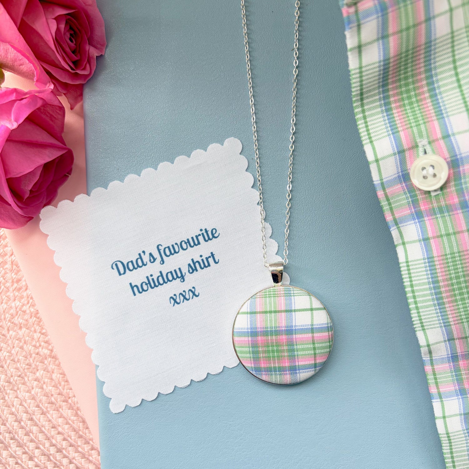 Necklace with a checked pendant with 'Dad's favourite holiday shirt xxx' text, surrounded by pink roses and plaid fabric.