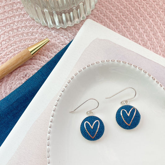 Heart-shaped earrings on a white dish with a pink background