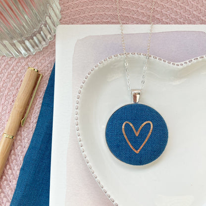 Heart denim blue pendant on a white dish with pink background