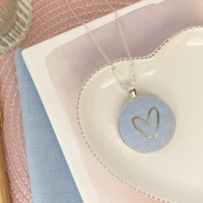 Necklace with a heart pendant on a pink surface