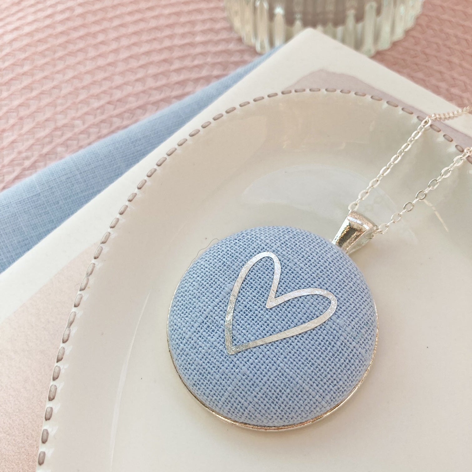 Necklace with a heart-shaped pendant on a soft pink and blue background