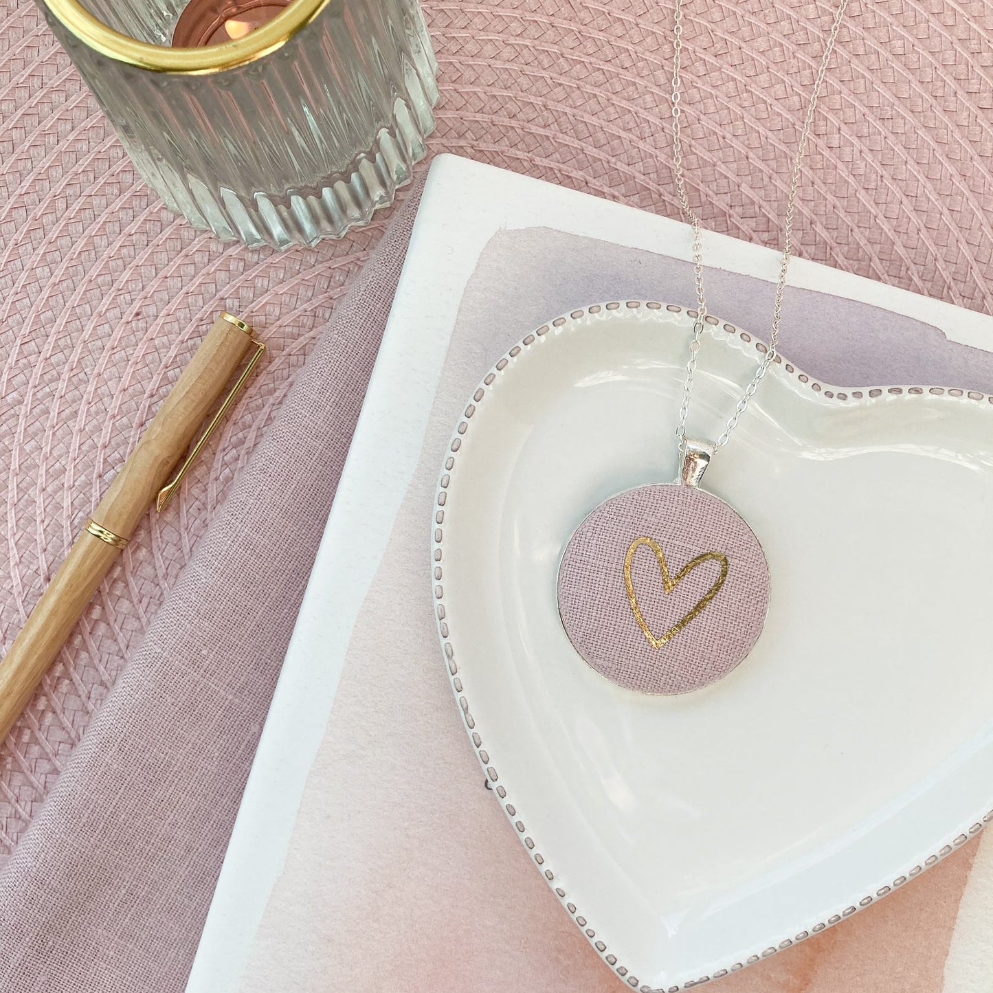 Pink and gold heart pendant on a white heart shaped dish