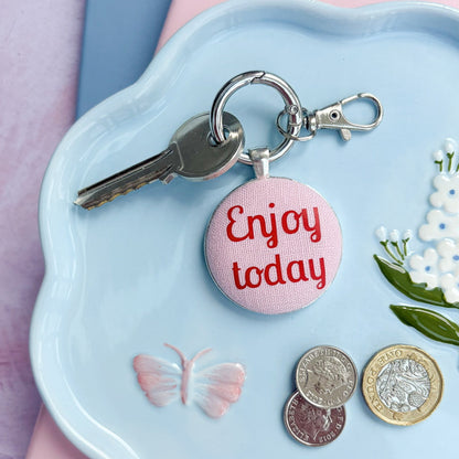 Keyring with 'Enjoy today' charm on a decorative plate with coins and keys