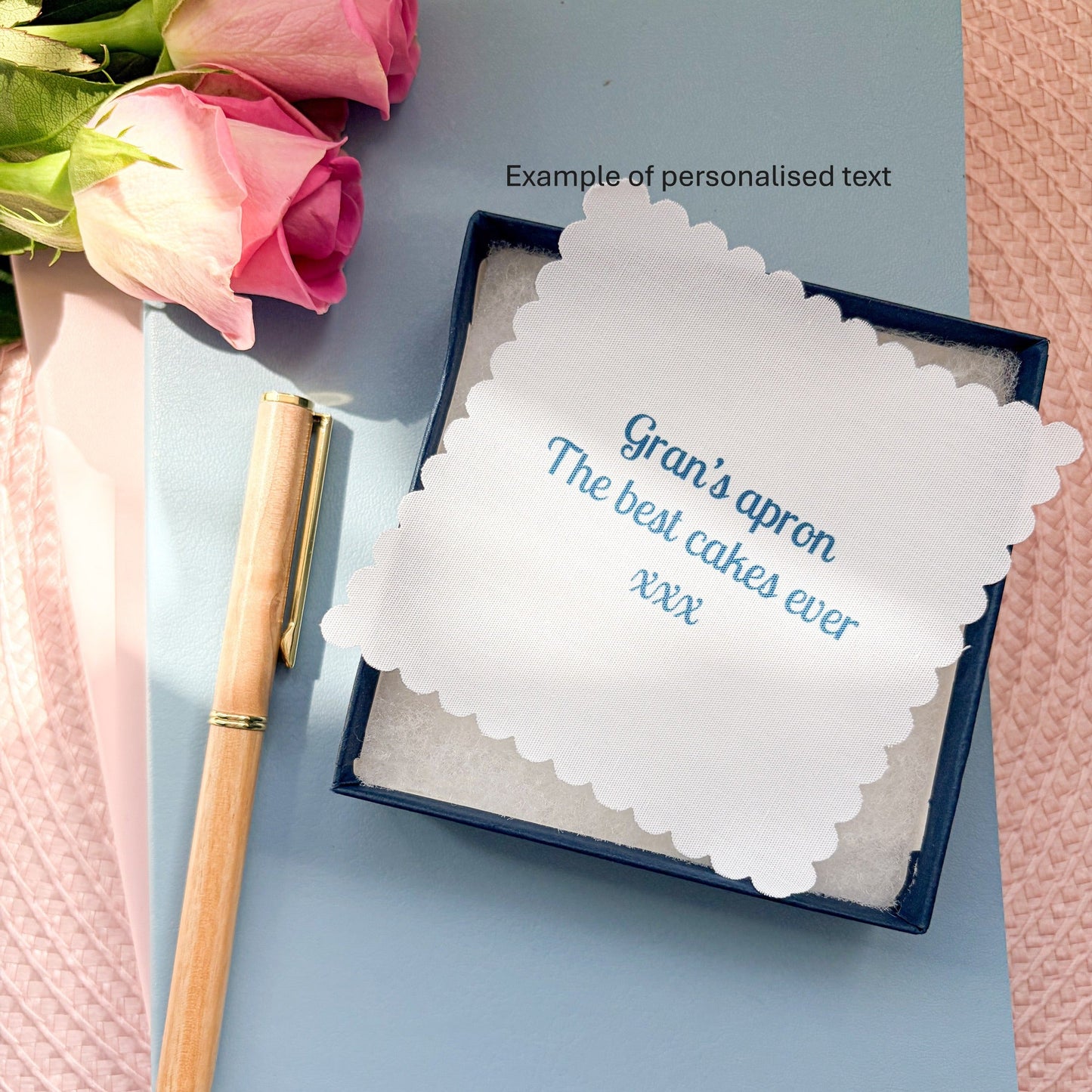 Grans apron memory keepsake gift box and fabric message, set on a blue notebook with a pen and rose