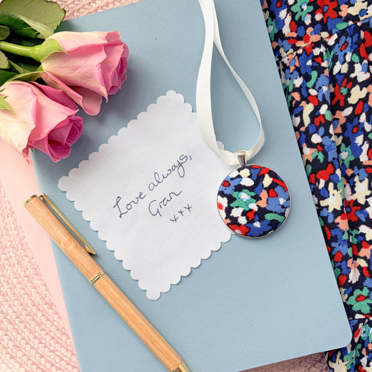Grans dress memory keepsake and fabric message, set on a blue notebook with pen and rose