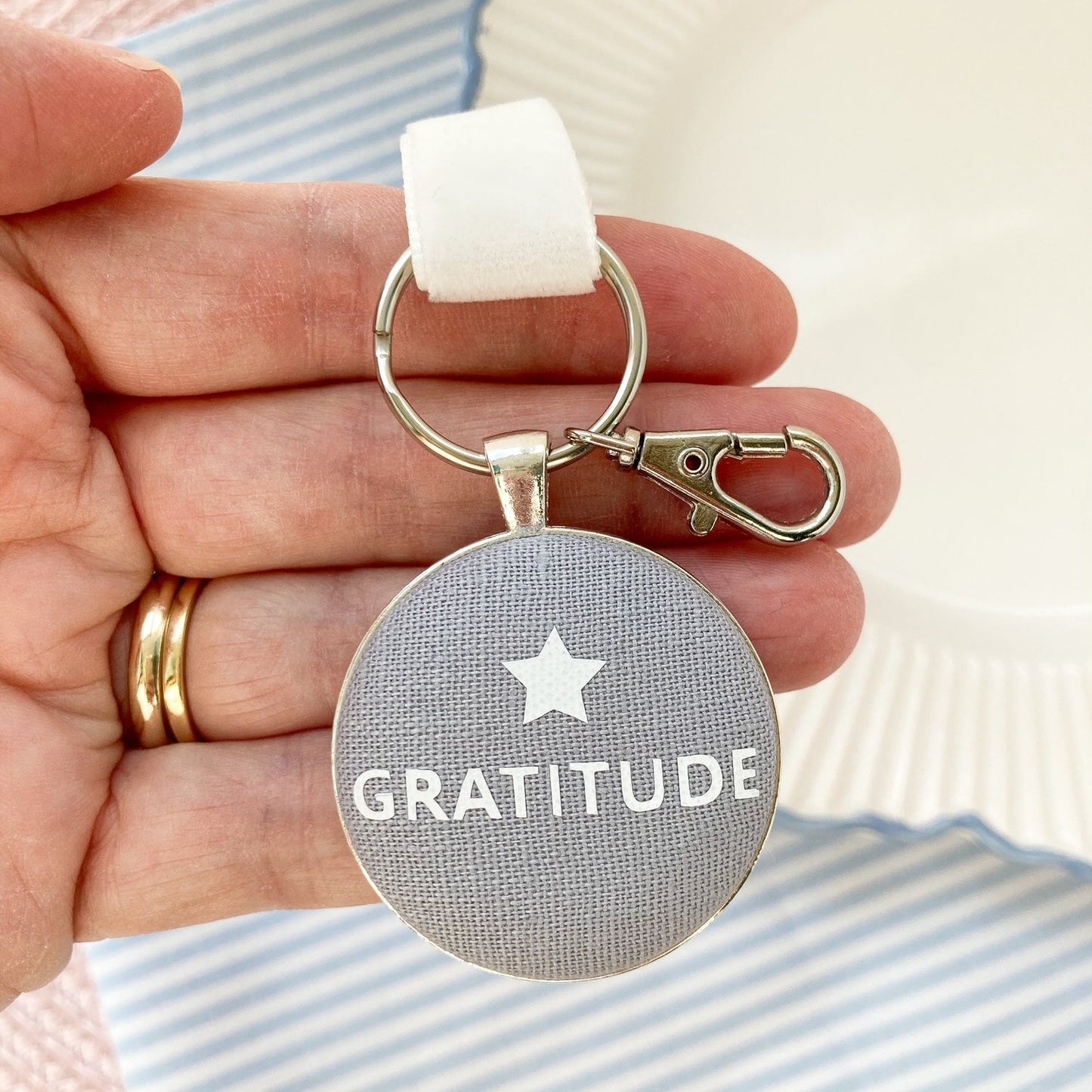 Keychain with 'GRATITUDE' and a star on a grey linen fabric