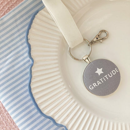 Keepsake with 'Gratitude' on a decorative plate with striped fabric background