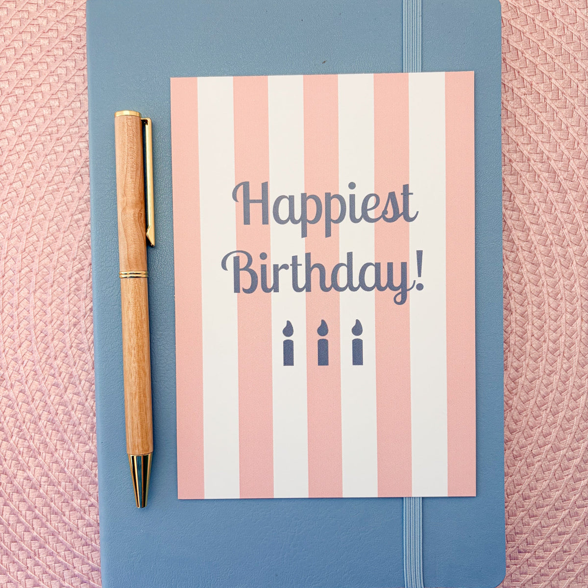 Happiest Birthday postcard with a pink and white striped design and blue candles