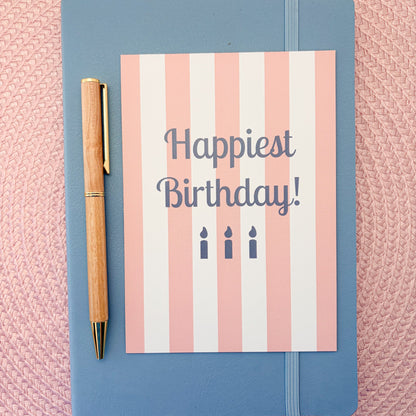 Happiest Birthday postcard with a pink and white striped design and blue candles