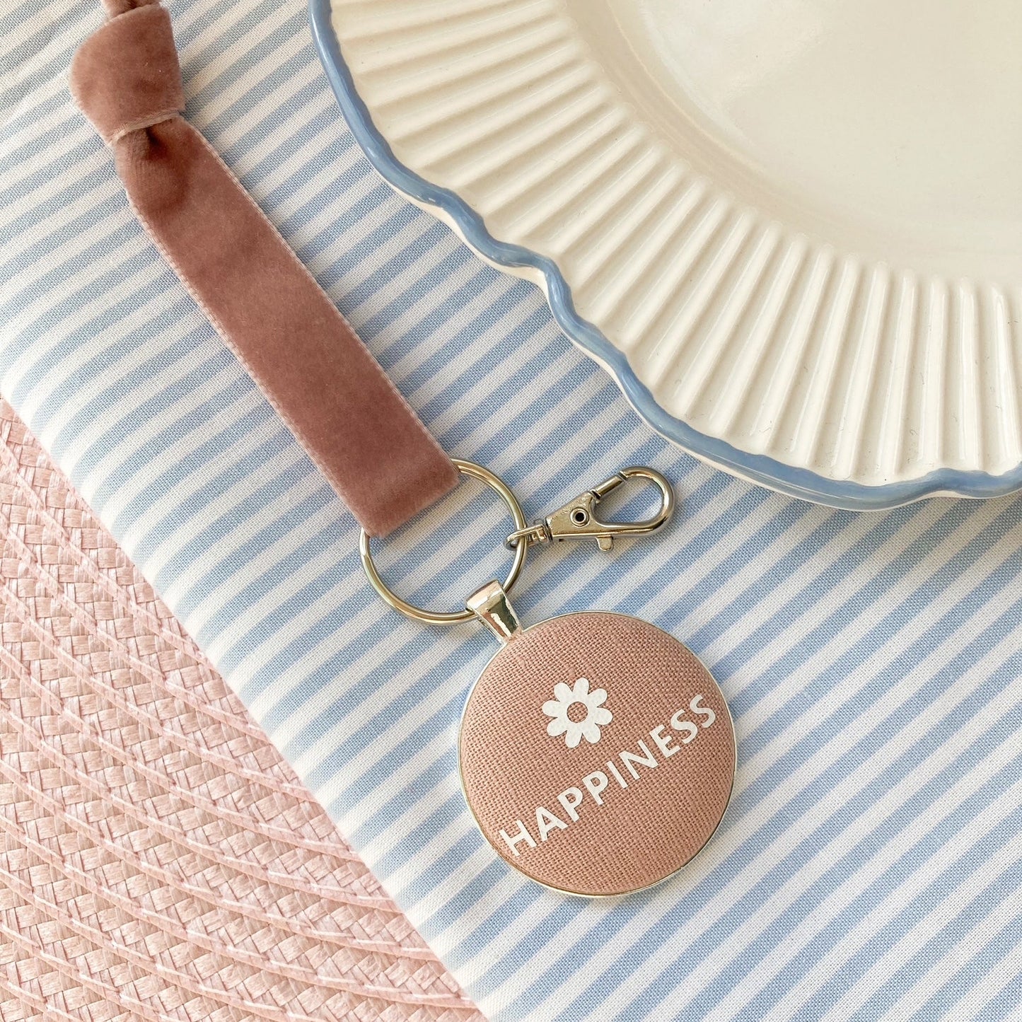 Key ring with 'Happiness' charm on a striped fabric background