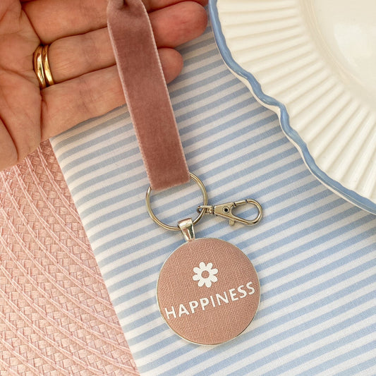Keychain with 'Happiness' and a flower in white printed onto pink blush fabric