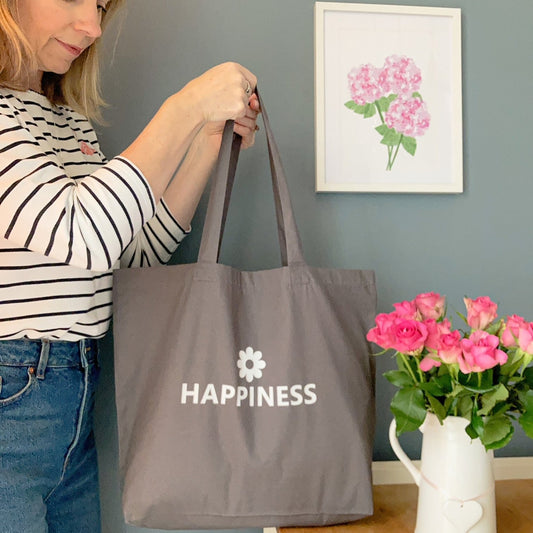 Grey tote bag printed with Happiness and a flower