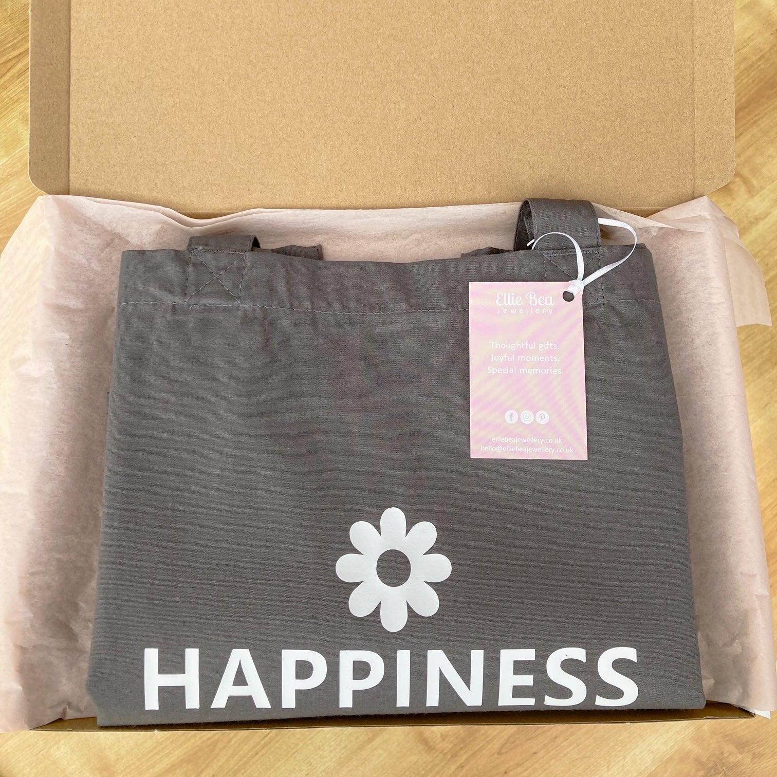 Happiness tote bag wrapped in tissue paper in a mailing box