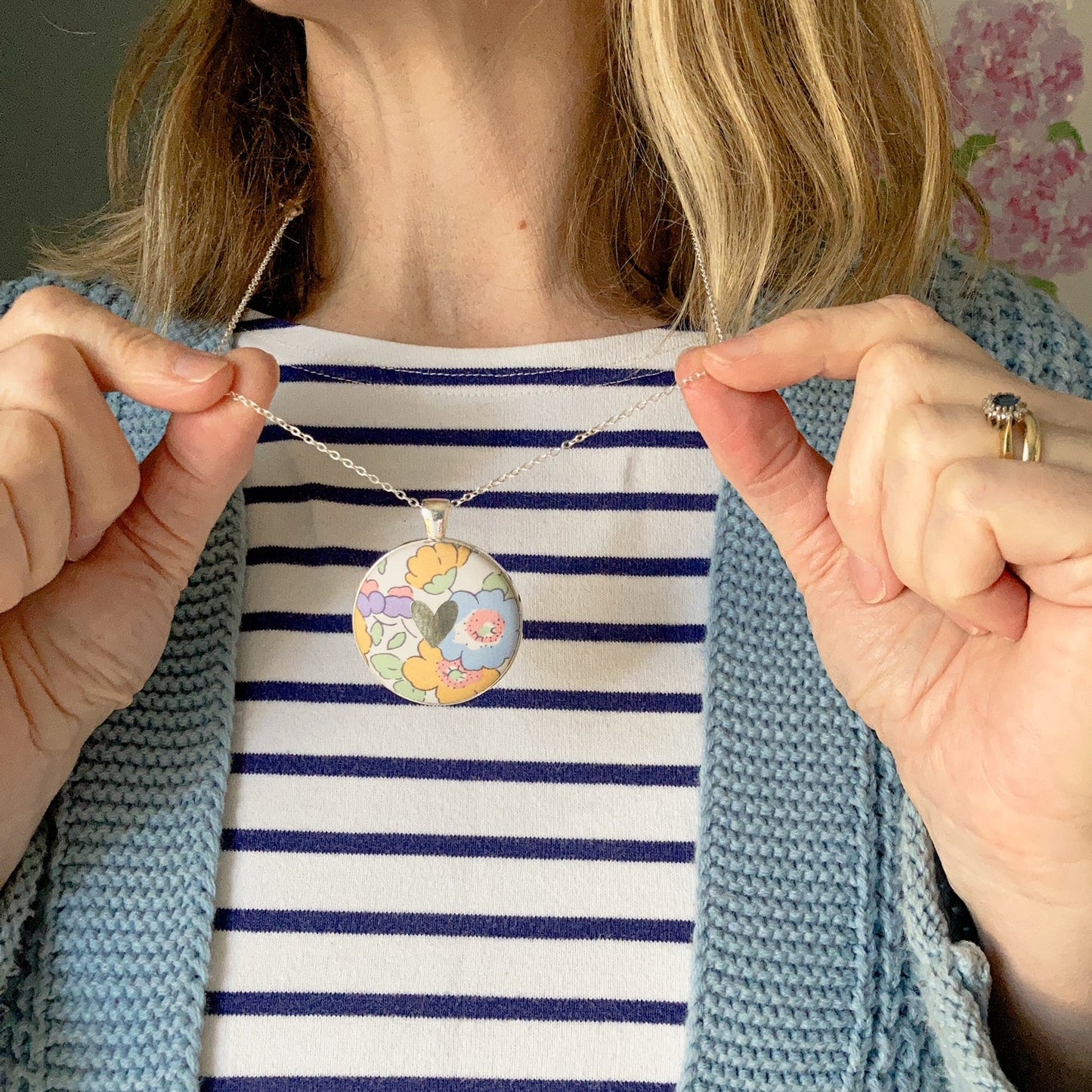 Pastel floral Liberty necklace with a silver heart worn by a lady with a blue striped top