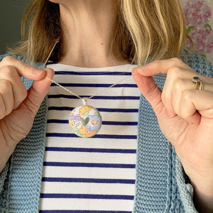 Pastel floral Liberty necklace with a silver heart worn by a lady with a blue striped top
