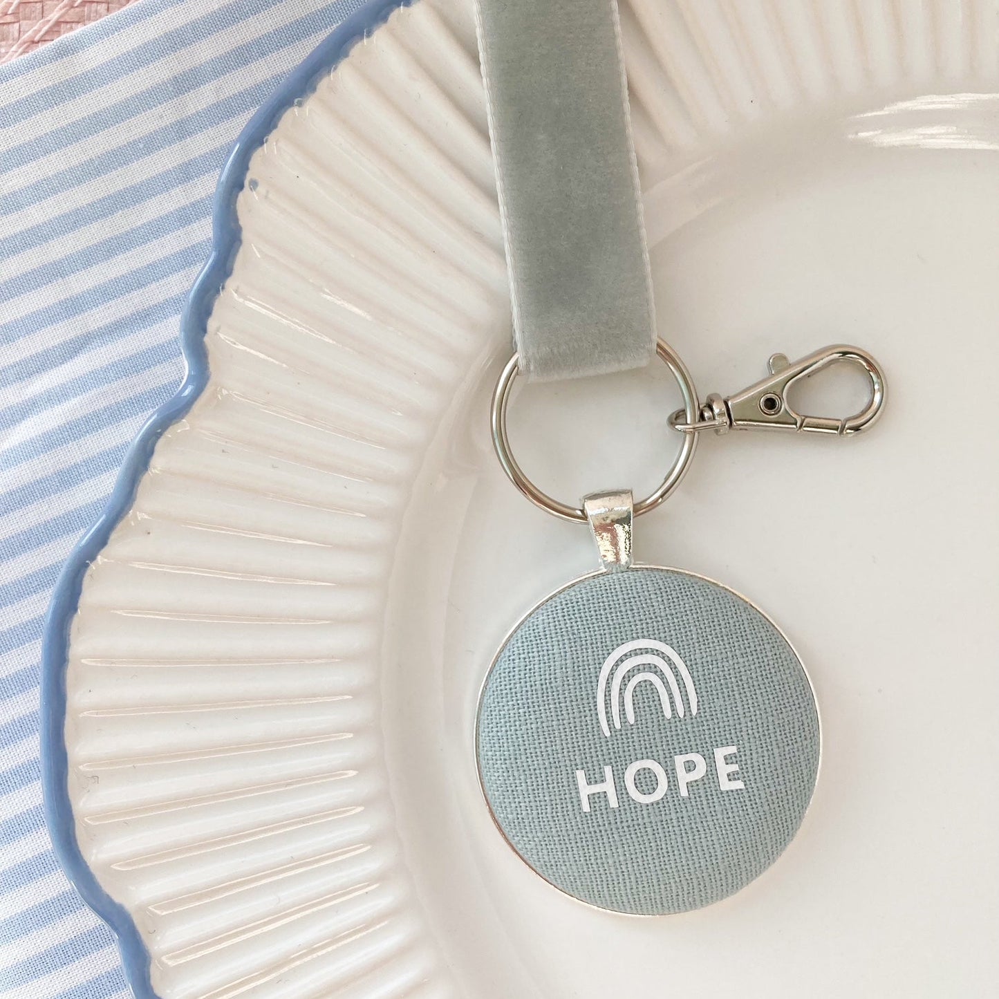 Keychain with 'HOPE' and rainbow symbol on a duck egg blue fabric