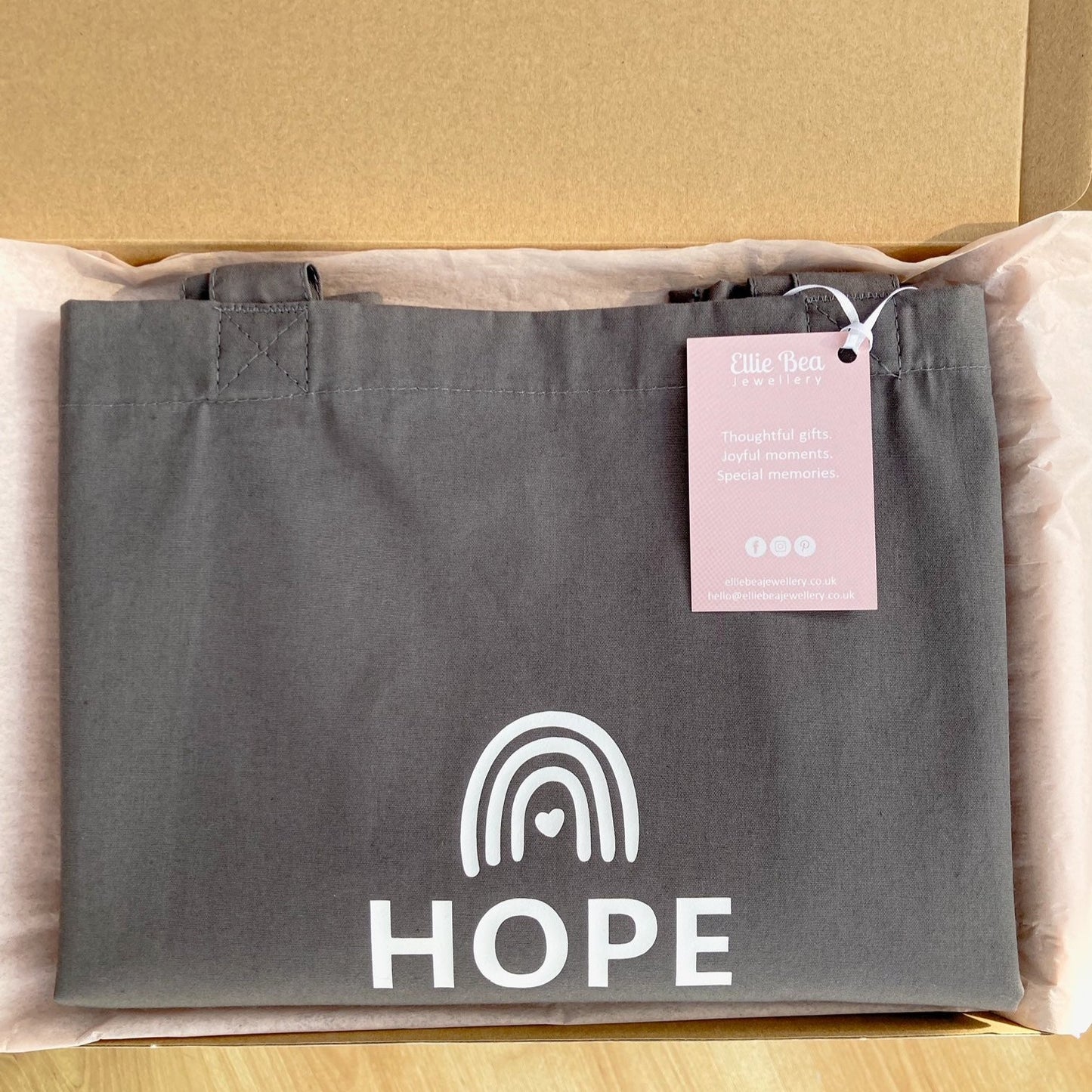 Grey Hope tote bag wrapped in tissue in a mailing box