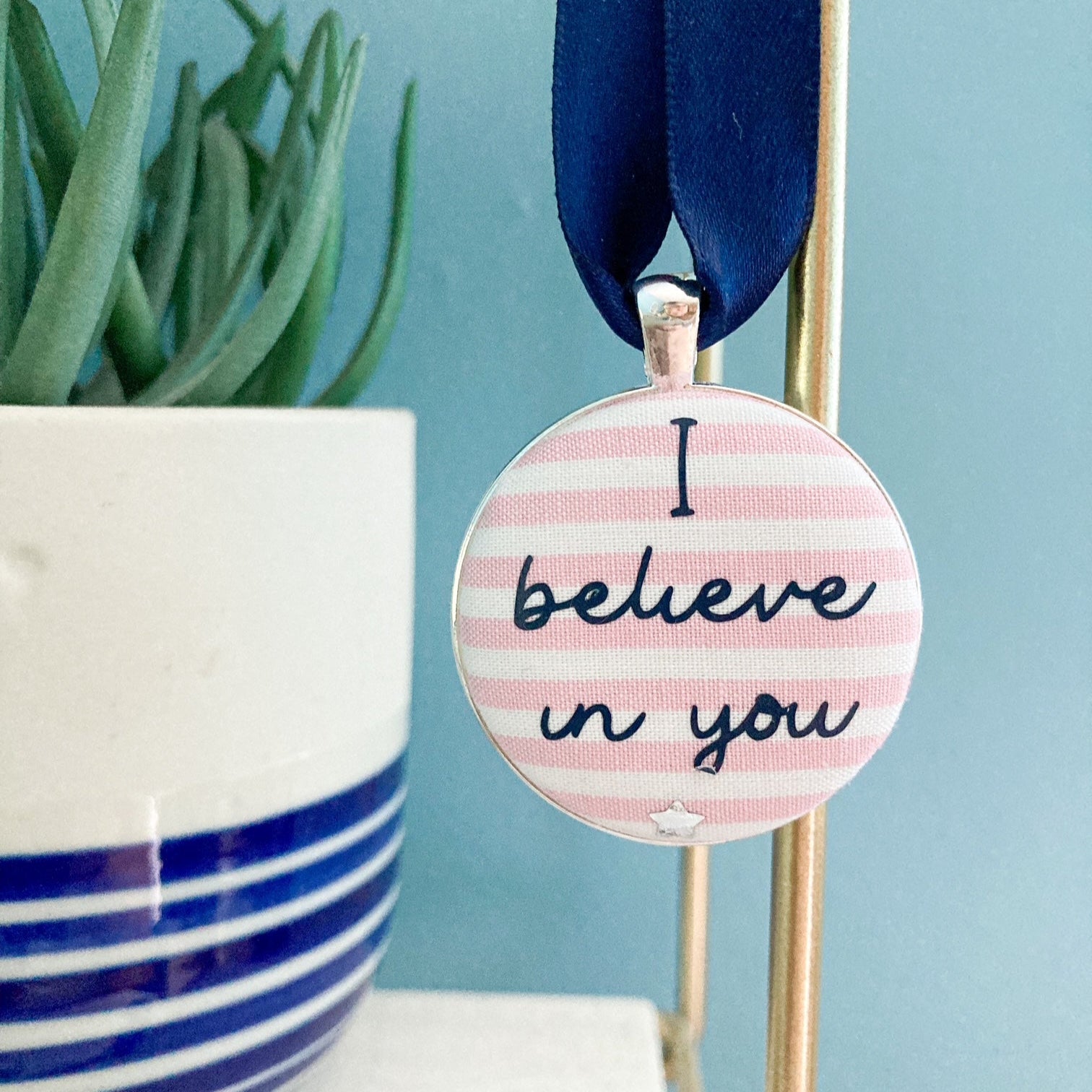 Keepsake with I believe in you printed onto pink and whtie striped fabric, with a navy blue ribbon