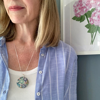 Woman wearing a teal & blue floral print necklace