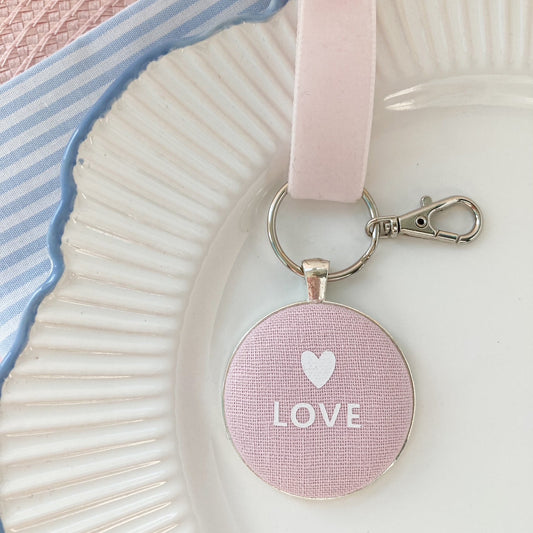 Pink keychain with 'LOVE' and heart symbol on pink fabric