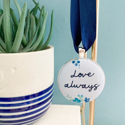 Keepsake with Love Always printed on a blue floral fabric with a navy blue ribbon