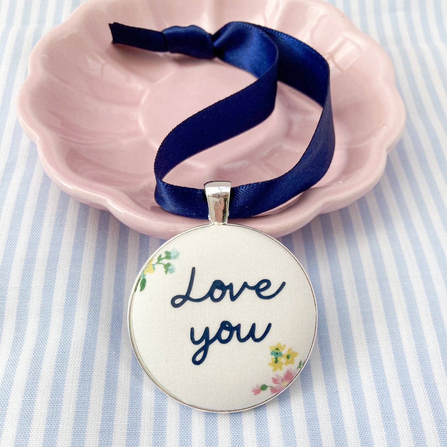 A Love You keepsake printed onto cream & floral fabric with a navy blue ribbon
