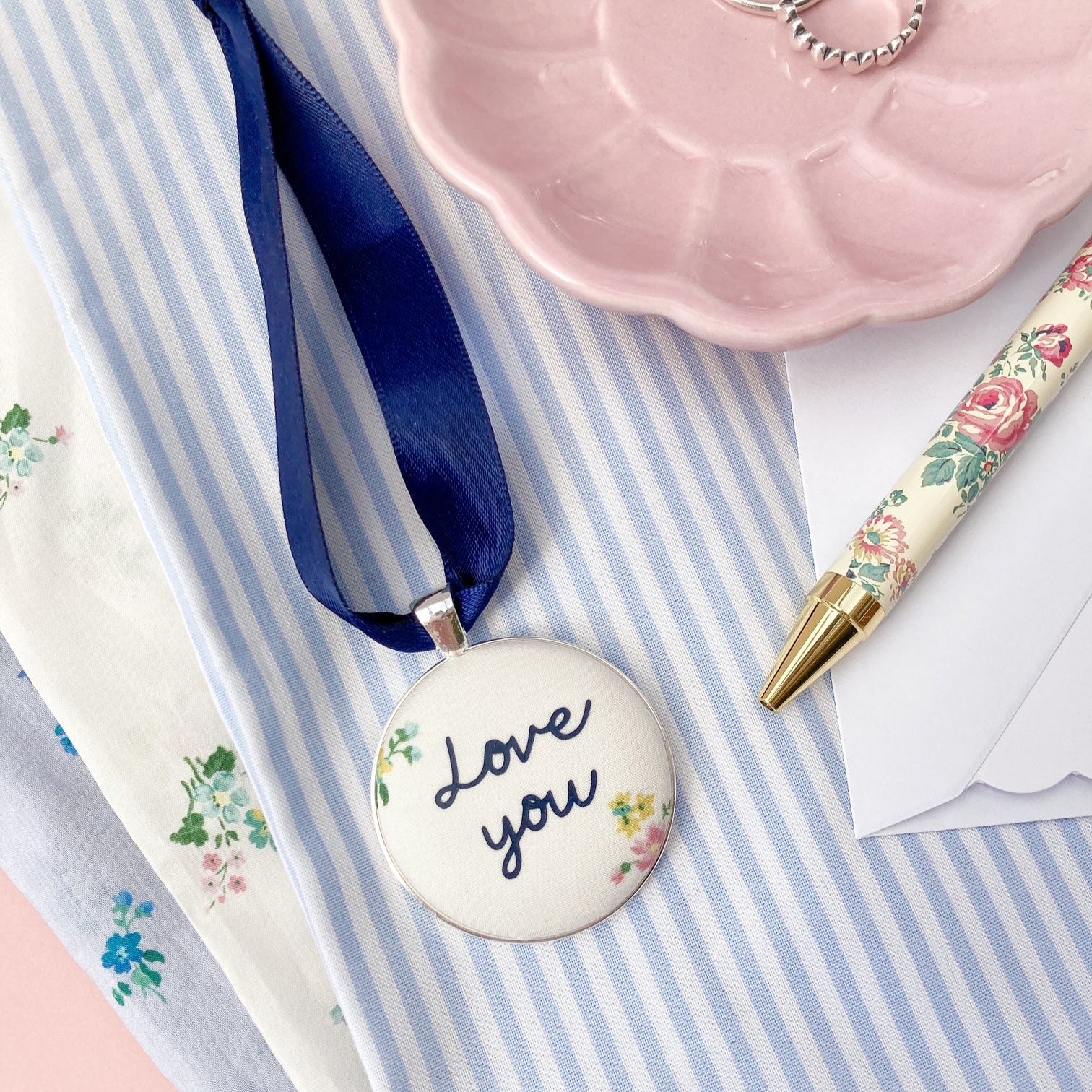 A Love You keepsake printed onto cream & floral fabric with a navy blue ribbon