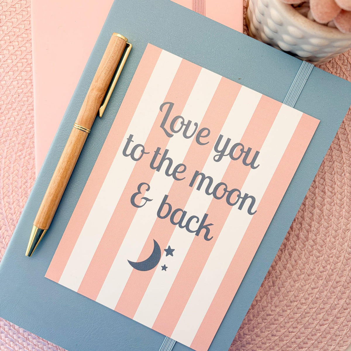 Love you to the moon & back postcard with a pink and white striped design with a moon and stars