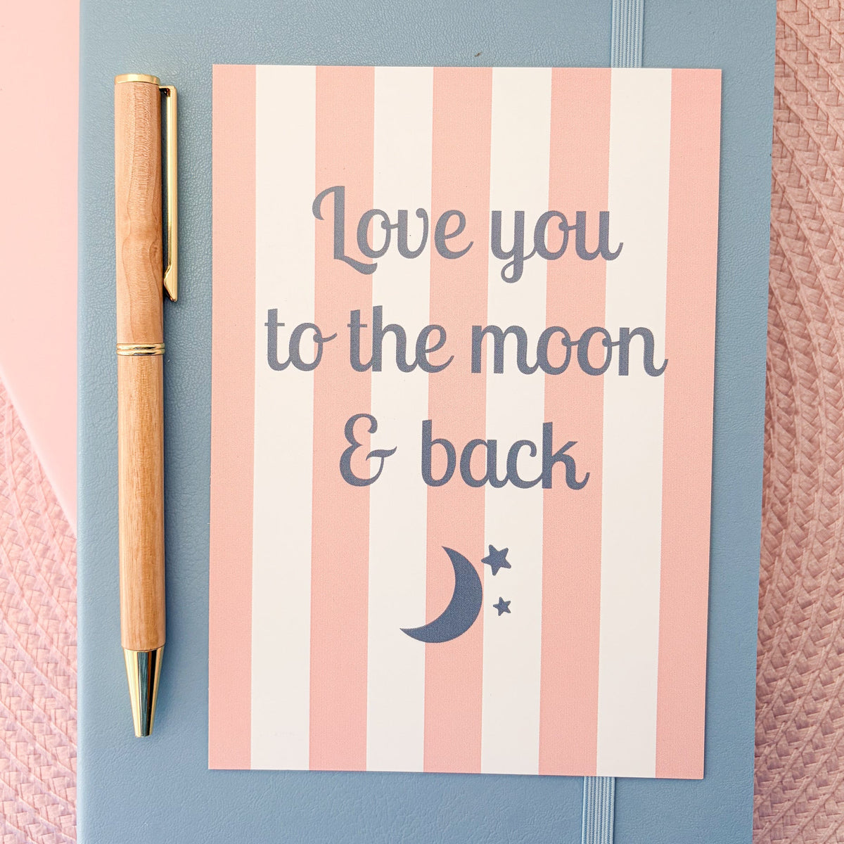 Love you to the moon & back postcard with a pink and white striped design with a moon and stars