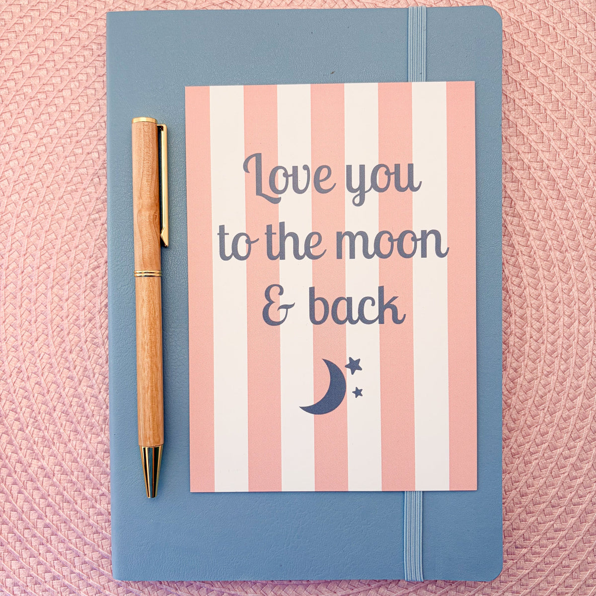Love you to the moon & back postcard with a pink and white striped design with a moon and stars