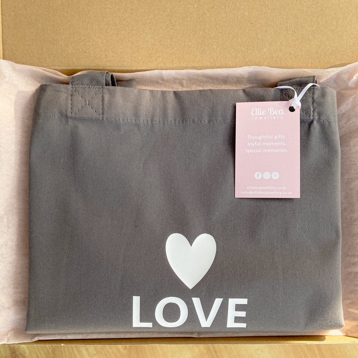 Love tote bag wrapped in tissue in a mailing box