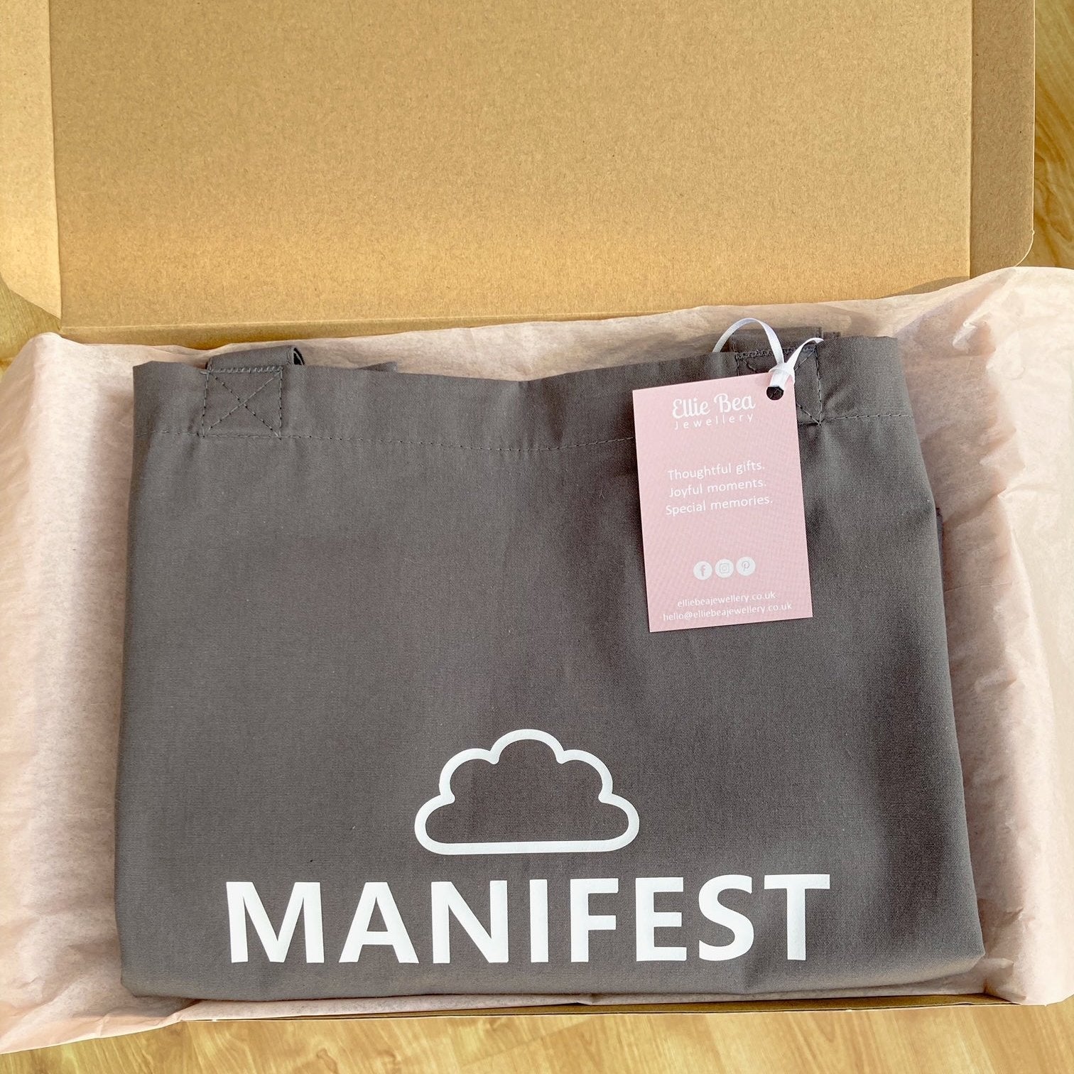 Manifest tote bag wrapped in tissue in a mailing box