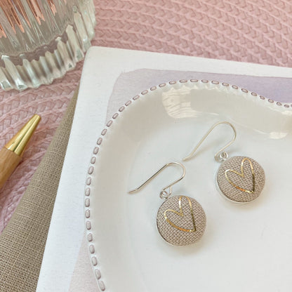Natural & silver heart earrings on a white jewelry dish with a pink textured surface
