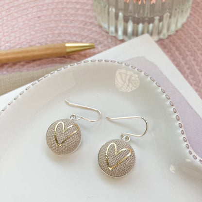 Natural & gold heart earrings on a white dish with a pink background