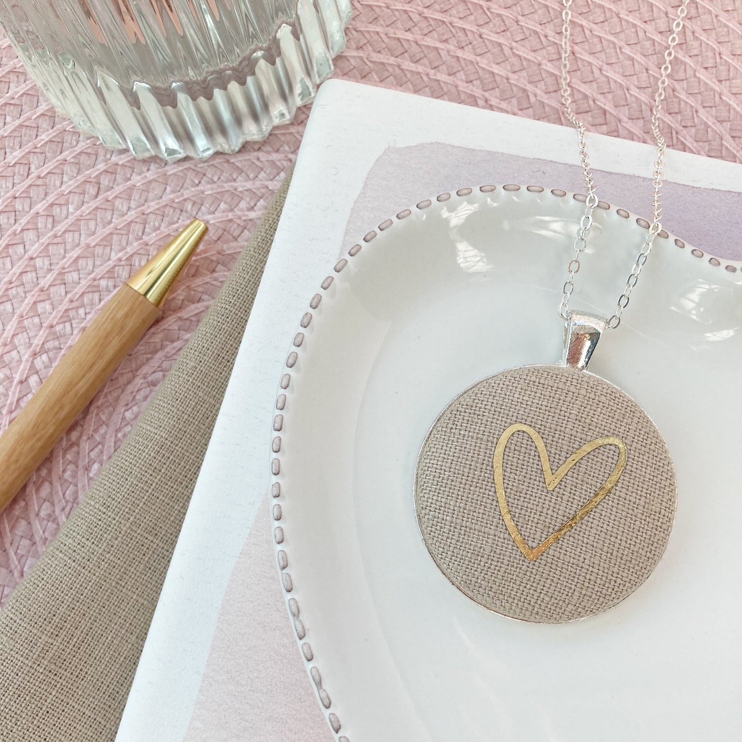 Necklace with a heart pendant on a white dish with a pink background