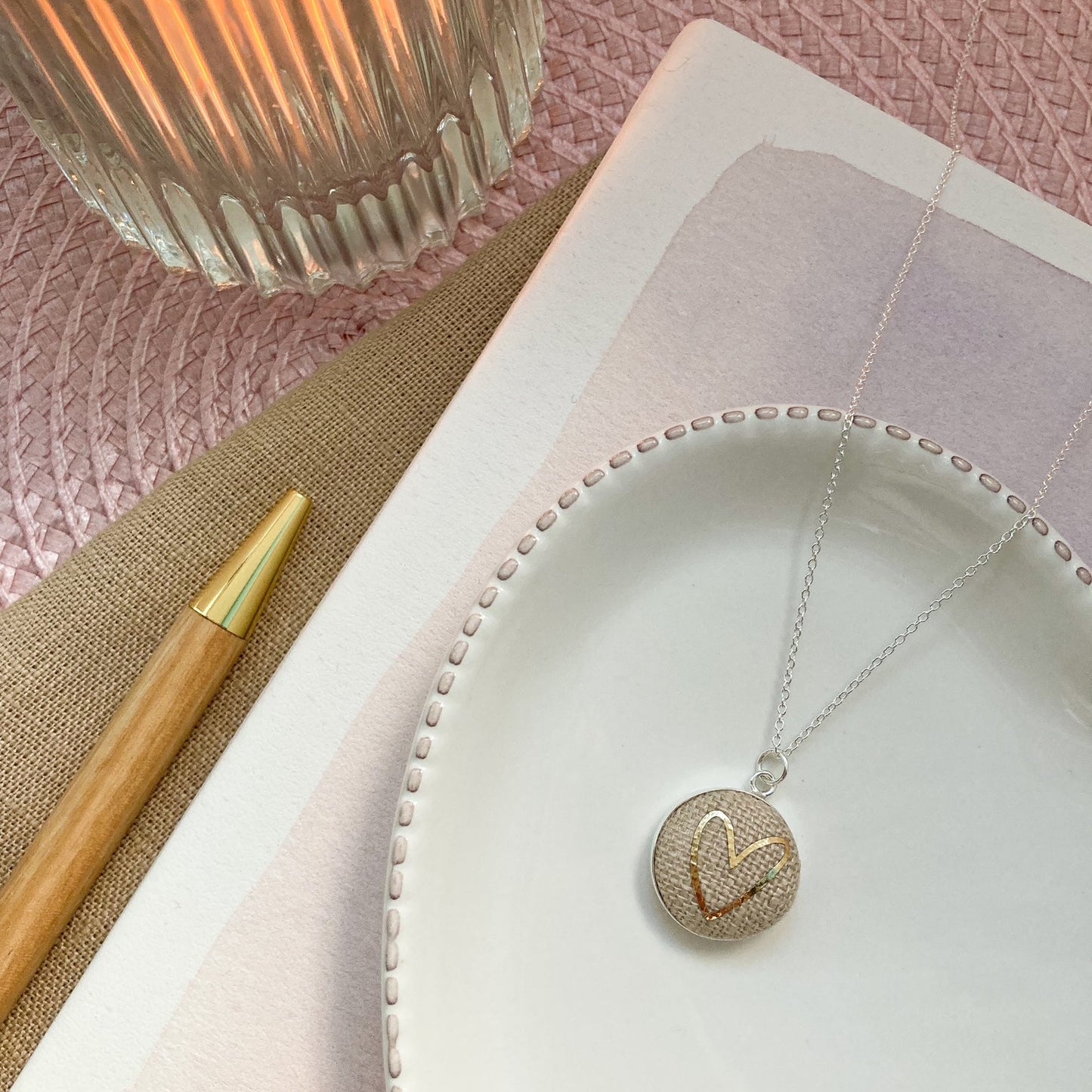 Necklace with a heart-shaped pendant on a white dish with a pink background