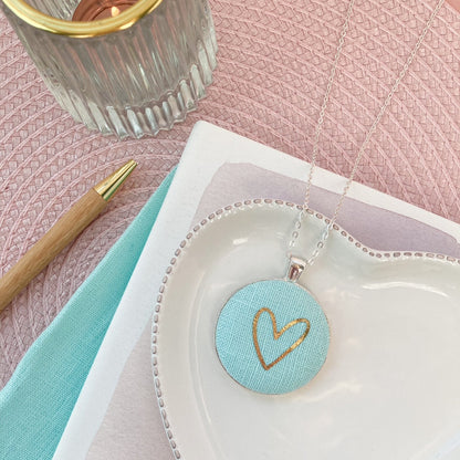 Jewelry dish with a heart-shaped pendant on a pink surface